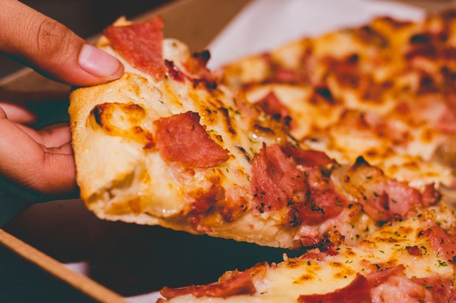 close up photo of person holding pizza 1653877 1